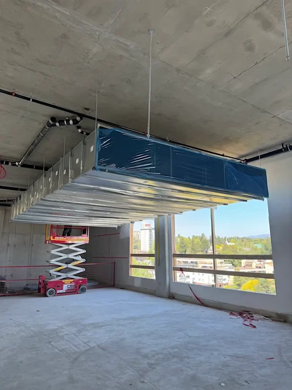Commercial mechanical room exhaust air ductwork – large rectangular galvanized exhaust duct hung from a concrete slab